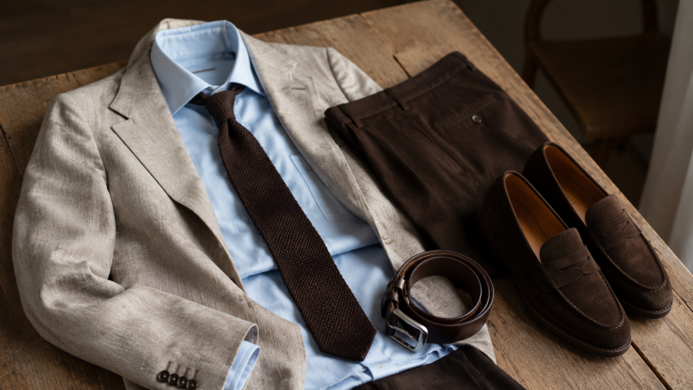 Detail of a navy jacket, grey trousers, shirt and loafers combination